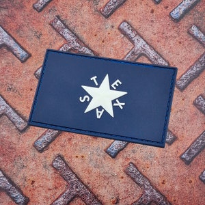 Op de afbeelding: Een blauwe patch met een witte ster en de letters "TEXAS" eromheen.