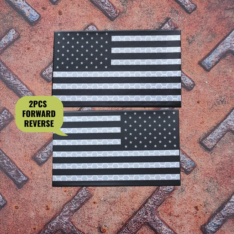 K&ouml;nnte beinhalten: Zwei schwarz-wei&szlig;e Aufn&auml;her der amerikanischen Flagge. Die Aufn&auml;her haben ein reflektierendes Wabenmuster auf den Streifen. Der Text "2PCS FORWARD REVERSE" befindet sich in einer gr&uuml;nen Sprechblase.