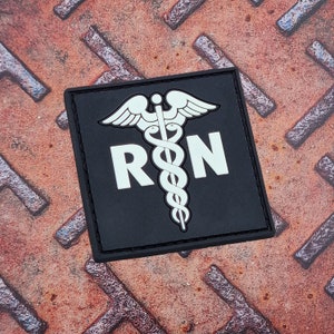 May include: Black and white embroidered patch with a medical caduceus symbol and the letters "RN" in white.