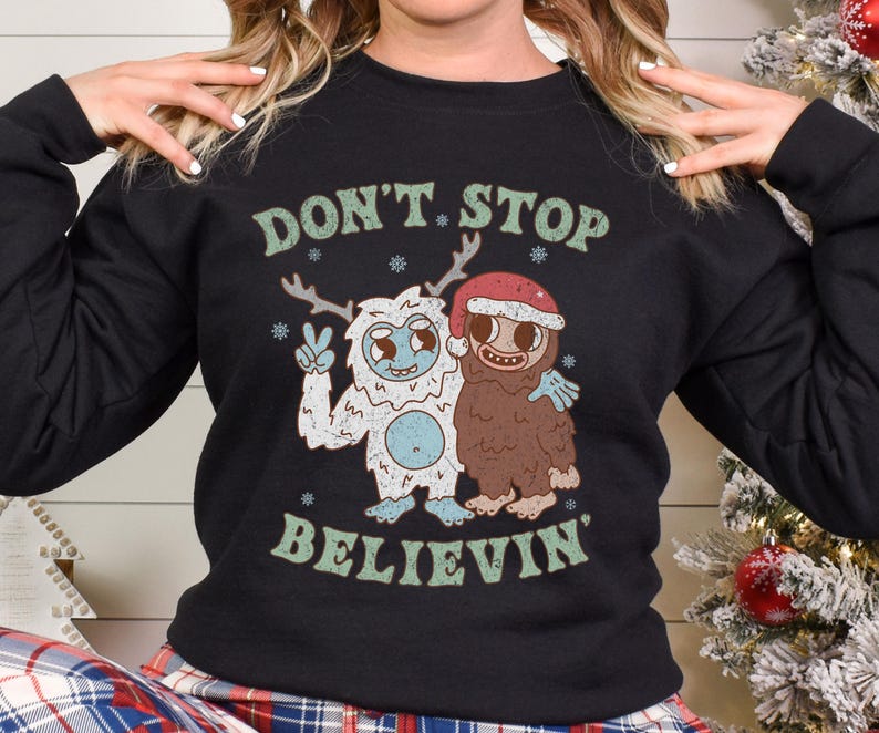 May include: Black sweatshirt with a white and green graphic of two cartoon monsters. The text "Don't Stop Believin'" is printed on the sweatshirt.