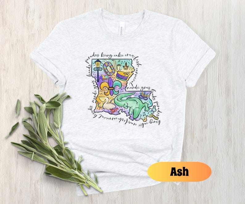 Op de afbeelding: Asgrijze T-shirt met een kleurrijke illustratie van de staat Louisiana met Mardi Gras-thema's en de tekst "parades king cake crawfish beads mardi gras floats parades".