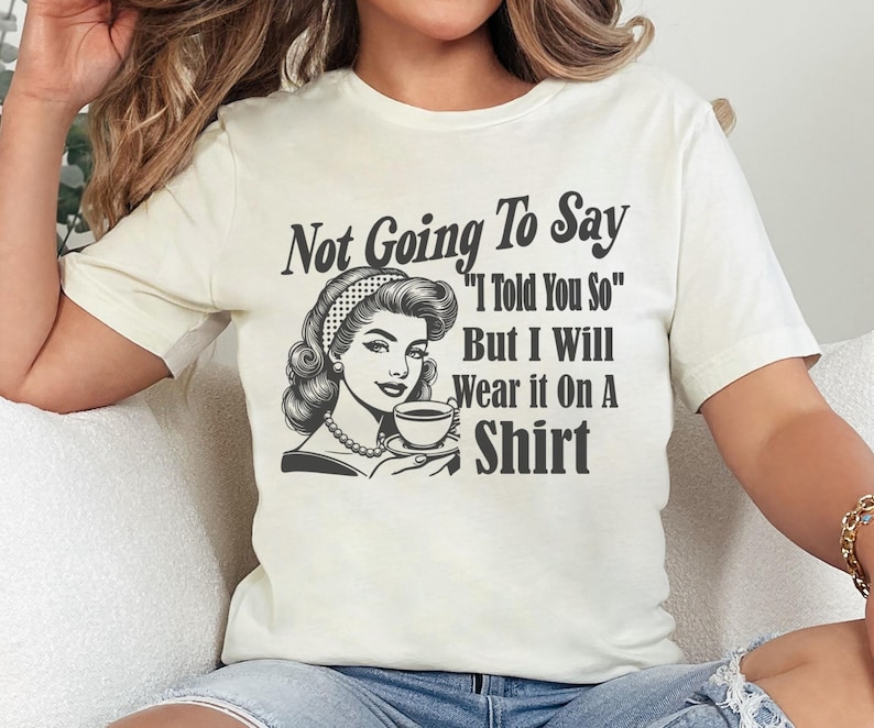 May include: White t-shirt with a black and white illustration of a woman holding a cup of coffee. The text on the shirt reads "Not Going To Say "I Told You So" But I Will Wear it On A Shirt"