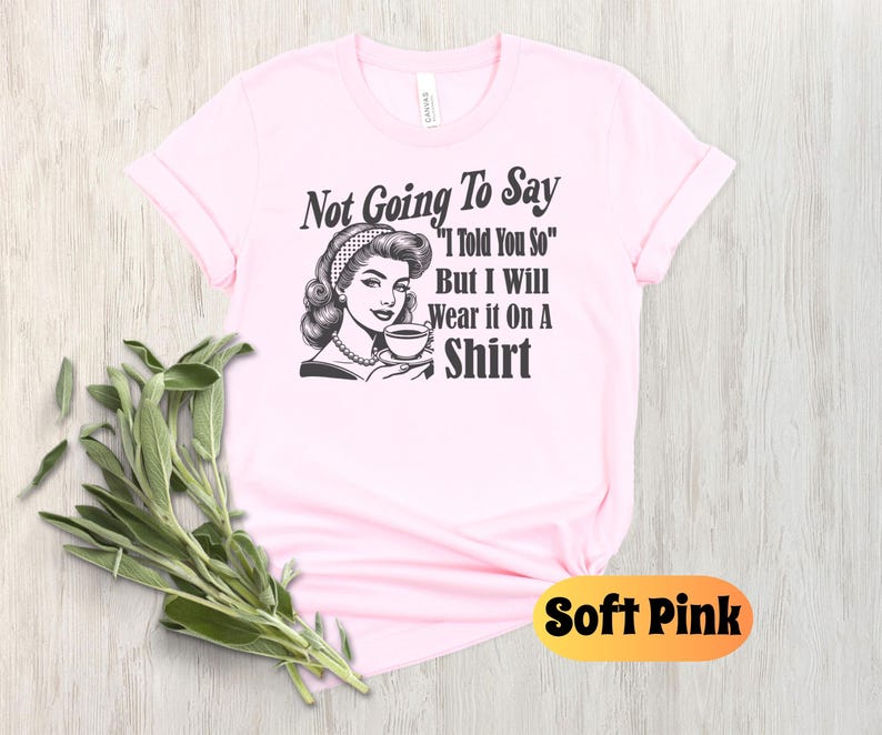 May include: A pink t-shirt with a black and white illustration of a woman holding a cup. The text on the shirt reads "Not Going To Say "I Told You So" But I Will Wear it On A Shirt".