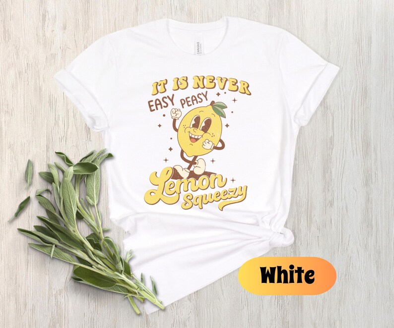 May include: White t-shirt with a yellow lemon graphic and the text "It is never easy peasy Lemon Squeezy".