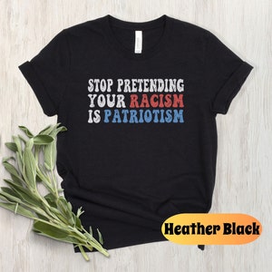 May include: Black t-shirt with the text "STOP PRETENDING YOUR RACISM IS PATRIOTISM" in red, white, and blue lettering. The shirt is a heather black color.