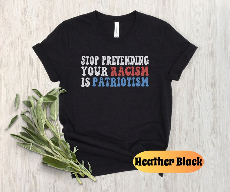 May include: Black t-shirt with the text "STOP PRETENDING YOUR RACISM IS PATRIOTISM" in red, white, and blue lettering. The shirt is a heather black color.