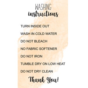 May include: A peach-colored watercolor background with black text outlining washing instructions: Turn inside out, Wash in cold water, Do not bleach, No fabric softener, Do not iron, Tumble dry on low heat, Do not dry clean. The text "Thank You!" is written in black cursive at the bottom.