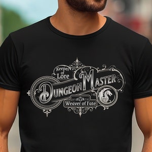 May include: Black t-shirt with a silver graphic design that says "Dungeon Master, Keeper of Lore, Weaver of Fate". The design features a dragon and a stylized D20.