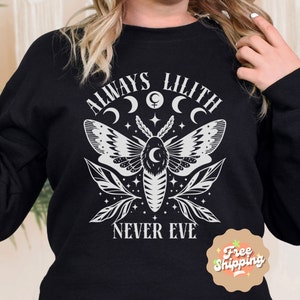 May include: Black sweatshirt with a white graphic design featuring a moth, crescent moons, stars, and the text "Always Lilith Never Eve".