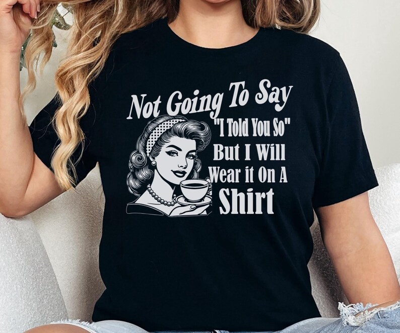 May include: Black t-shirt with a white graphic of a woman holding a cup of coffee. The text on the shirt reads "Not Going To Say "I Told You So" But I Will Wear it On A Shirt"