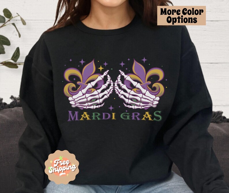 May include: Black sweatshirt with a purple and gold Mardi Gras design featuring two skeletal hands holding a fleur-de-lis. The text "Mardi Gras" is printed below the design.