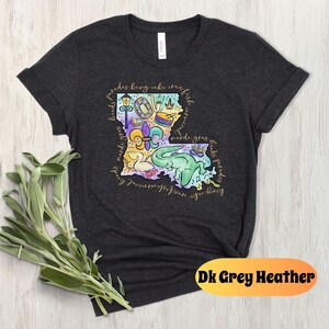 Op de afbeelding: Donkergrijs heather t-shirt met een kleurrijke illustratie van de staat Louisiana met Mardi Gras-thema-iconen en de tekst "Friends bring cake, craft beer, and good times. Mardi Gras beads, floats, parades, king cake, crawfish, and music.  NOLA, New Orleans, Lafayette, Baton Rouge, Shreveport, Lake Charles, and more."