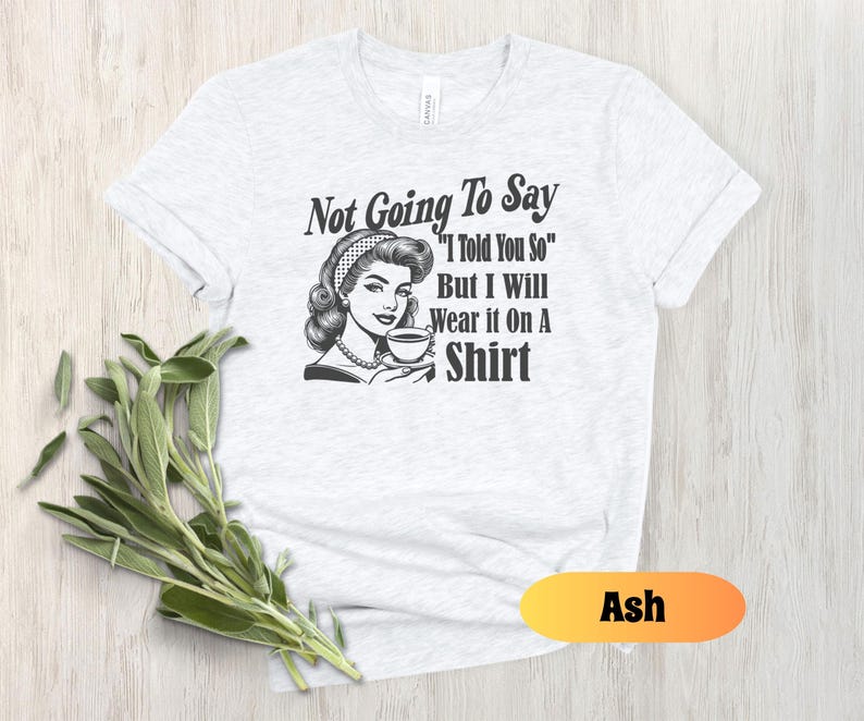 May include: A white t-shirt with a black and white illustration of a woman drinking coffee. The text on the shirt reads "Not Going To Say "I Told You So" But I Will Wear it On A Shirt".