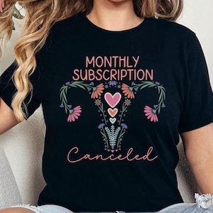 May include: Black t-shirt with a floral design of a uterus and the text "Monthly Subscription Canceled".