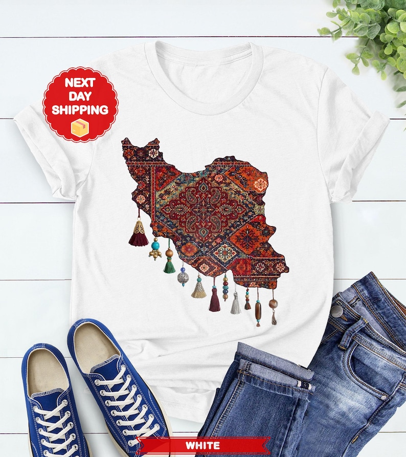 May include: White t-shirt featuring a detailed map of Iran, filled with a traditional rug design in red, blue, and gold. The shirt has decorative tassels and is paired with blue jeans and sneakers. The text "NEXT DAY SHIPPING" is visible.