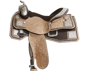 May include: A brown leather saddle with silver accents and floral tooling. The saddle has a  tooled leather seat and a  tooled leather skirt. The saddle is decorated with silver conchos and a silver horn.