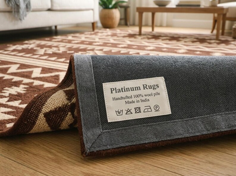 May include: A rolled-up brown and cream-colored area rug with a geometric pattern. The rug's underside is gray, with a label that reads "Platinum Rugs, Handtufted 100% wool pile, Made in India."