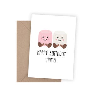 May include: A white birthday card with a brown envelope. The card shows two cartoon marshmallows with smiling faces and the text "HAPPY BIRTHDAY NAME!". One marshmallow is pink, the other is white.
