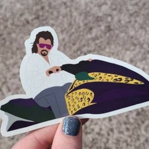 May include: A sticker of a cartoon man wearing sunglasses and a white shirt, driving a purple and yellow jet ski with a leopard print design.
