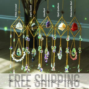 May include: Five hanging geometric crystal suncatchers with gold frames and chains. Each holds a different crystal: White Crystal, Lapis Lazuli, Amethyst, Opal-Synthesis, and Watermelon Red. The suncatchers are adorned with dangling beads and charms.