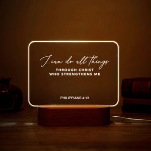 May include: A rectangular LED night light with the text "I can do all things through Christ who strengthens me" and "Philippians 4:13". The light has a wooden base and a glowing white frame.