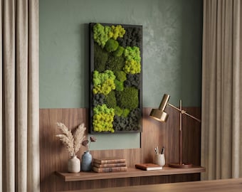 Peut inclure: Un tableau mural rectangulaire avec un cadre noir, orné de mousse préservée dans des tons de vert et de jaune. L'œuvre est accrochée sur un mur vert. Une étagère en bois en dessous présente des objets décoratifs. La pièce est décorée de rideaux neutres.