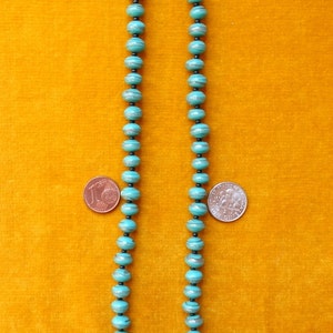 May include: A turquoise blue beaded necklace with silver accents. The beads are round and have a slightly textured surface. The necklace is approximately 46 cm long.