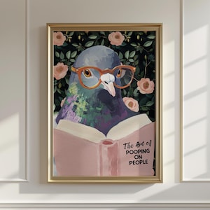 May include: Framed art print featuring a pigeon wearing orange glasses, reading a book with the text "The Art of Pooping on People." The background has a floral pattern with pink roses and green leaves. The frame is gold.