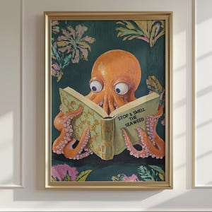 Pode incluir: Uma impressão artística emoldurada com um polvo laranja lendo um livro com o texto "STOP & SMELL THE SEAWEED". O polvo tem olhos grandes e está rodeado por um fundo verde escuro com detalhes florais. A moldura é dourada.