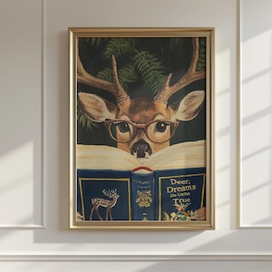May include: A framed print featuring a deer wearing glasses and reading a book. The book has a blue cover with gold lettering and a deer illustration. The text on the book reads "Deer, Dreams Do Come True."