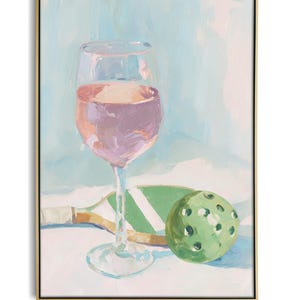 K&ouml;nnte beinhalten: Ein &Ouml;lgem&auml;lde zeigt ein Weinglas mit rosa Fl&uuml;ssigkeit, einen gr&uuml;nen Pickleball und einen Schl&auml;ger. Der Hintergrund ist eine weiche Mischung aus Blau und Wei&szlig;. Das Kunstwerk ist in einem goldfarbenen Rahmen gerahmt.