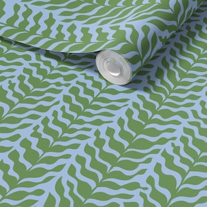 May include: A roll of wallpaper featuring a repeating pattern of green, leaf-like shapes against a light blue background. The design has a modern, organic feel, with a slight wave effect in the leaves. The roll is partially unrolled, showing the pattern.