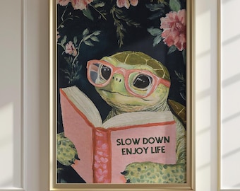 以下が含まれることがあります： ピンク色のメガネをかけたカメが「SLOW DOWN ENJOY LIFE」と書かれた本を読んでいる額入りのアートプリント。背景は、ピンクの花が咲く暗い花柄です。フレームは金色です。
