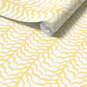 May include: A roll of wallpaper featuring a repeating pattern of yellow, organic shapes against a white background. The design has a flowing, wavy appearance, creating a textured visual effect. The wallpaper is partially unrolled, revealing the pattern.
