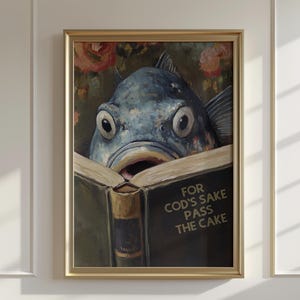 May include: A framed art print featuring a blue fish with large eyes, reading a book. The book's cover reads "FOR COD'S SAKE PASS THE CAKE". The background includes floral elements.