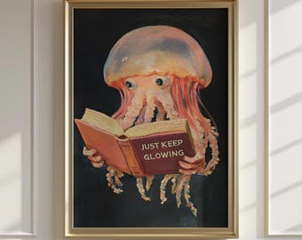 May include: A framed art print featuring a jellyfish reading a book. The jellyfish is depicted in shades of pink, orange, and white, with the book in its tentacles. The book's cover reads "JUST KEEP GLOWING" in white text against a maroon background.