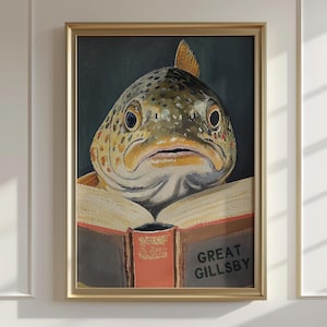 May include: Framed artwork featuring a fish with a serious expression, appearing to read a book. The book has a red cover and the title "GREAT GILLSBY" is visible. The fish has a speckled pattern and is set against a dark green background.