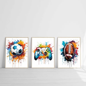 Könnte beinhalten: Drei gerahmte Kunstdrucke mit einem Fußball, einem Videospiel-Controller und einem Football. Jedes Bild hat einen weißen Hintergrund mit bunten Farbspritzereffekten. Der Fußball ist schwarz-weiß mit blauen Akzenten.