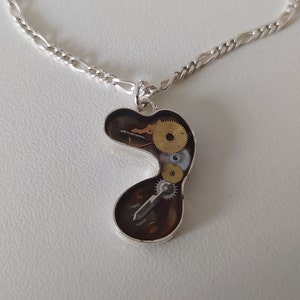 A steampunk style pendant, made with sterling silver with upcycled original clock parts and eco resin, with silver chain or  nylon cord.