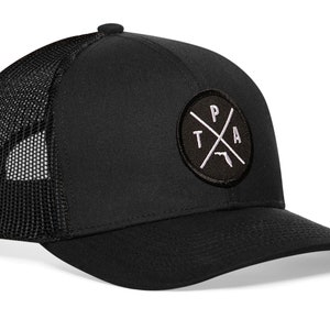 May include: Black trucker hat with a black and white embroidered patch featuring a circle with a cross inside and the letters "TPA" and the outline of Florida.