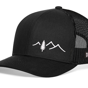 May include: Black trucker hat with a mesh back and a curved brim. The front panel features a white embroidered mountain and tree design. A small square tag with the letter "H" is on the side.
