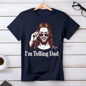 May include: A navy blue t-shirt with a graphic of Jesus wearing sunglasses and the text "I'm Telling Dad".