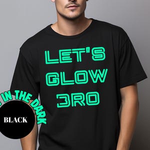 May include: Black t-shirt with the text "LET'S GLOW BRO" in bright green, outlined letters. A circular graphic at the bottom left reads "GLOW IN THE DARK" and "BLACK". The shirt is a casual, unisex style.