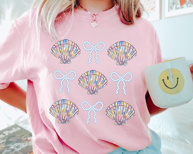 Comfort Colors t-shirt with a seashell and bow design, perfect for beach days, coastal vibes, and summer outings with a preppy aesthetic