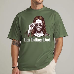 May include: A green t-shirt with a cartoon image of Jesus wearing sunglasses and the text "I'm Telling Dad".