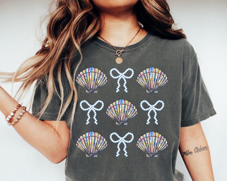 Comfort Colors t-shirt with a seashell and bow design, perfect for beach days, coastal vibes, and summer outings with a preppy aesthetic