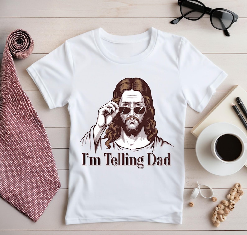 May include: White t-shirt with a drawing of Jesus wearing sunglasses and the text "I'm Telling Dad".