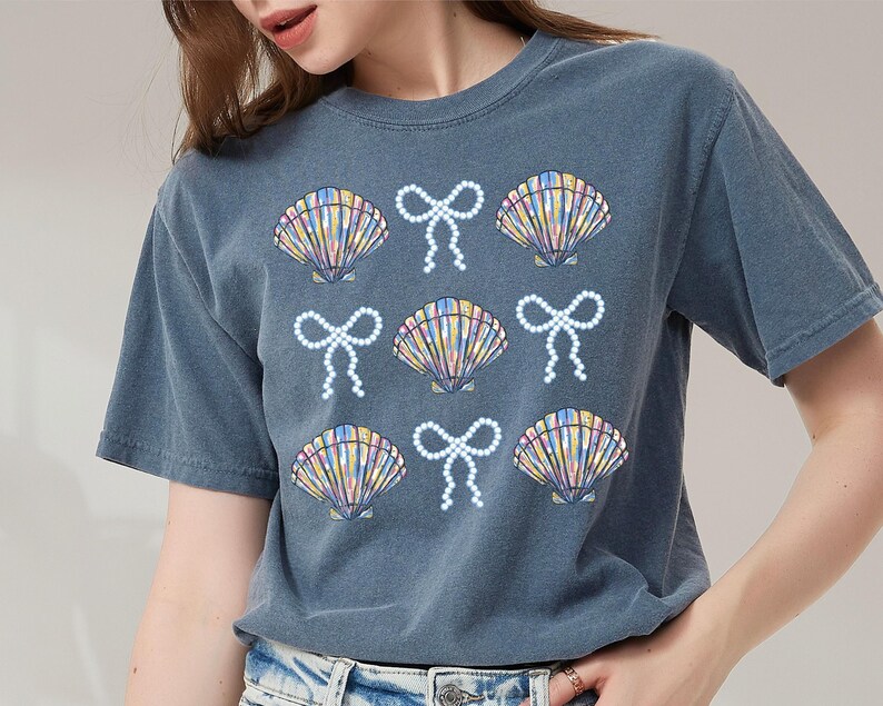 Comfort Colors t-shirt with a seashell and bow design, perfect for beach days, coastal vibes, and summer outings with a preppy aesthetic