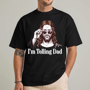 May include: Black t-shirt with a graphic of Jesus wearing sunglasses and the text "I'm Telling Dad".
