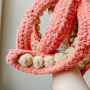 May include: A crocheted octopus toy with pink and beige yarn. The octopus has eight tentacles and a round head with a textured surface.